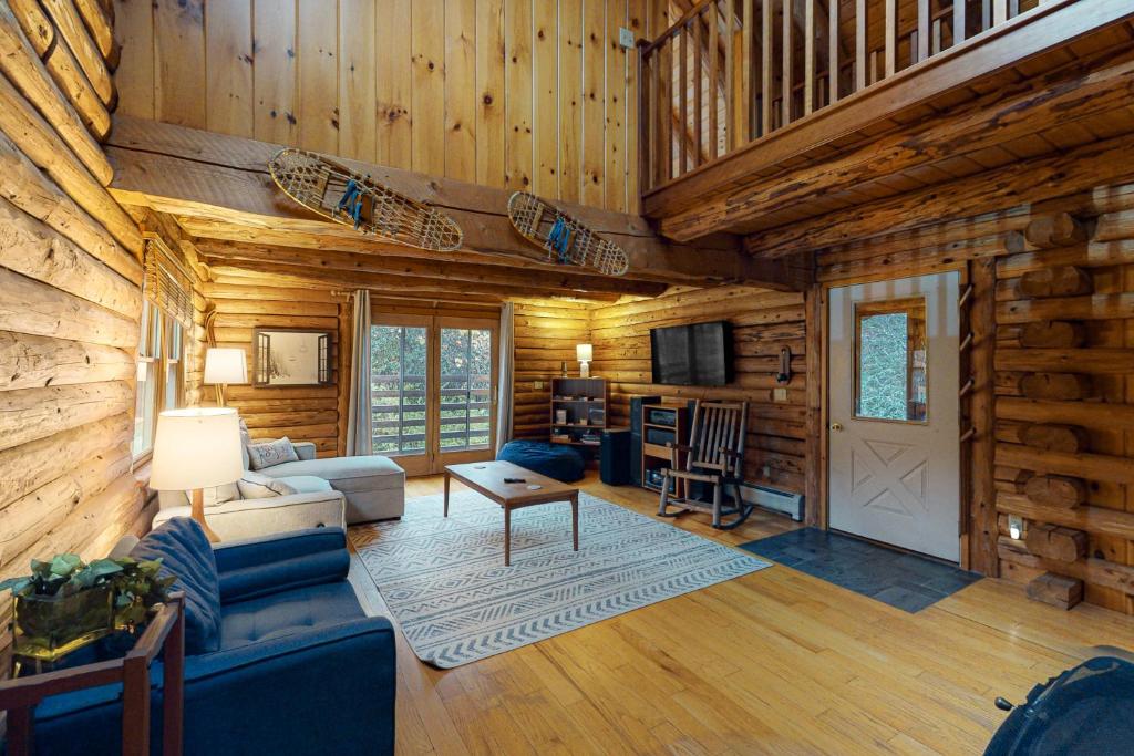 una sala de estar en una cabaña de madera con sofá y mesa en Hartland Cabin en Hartland