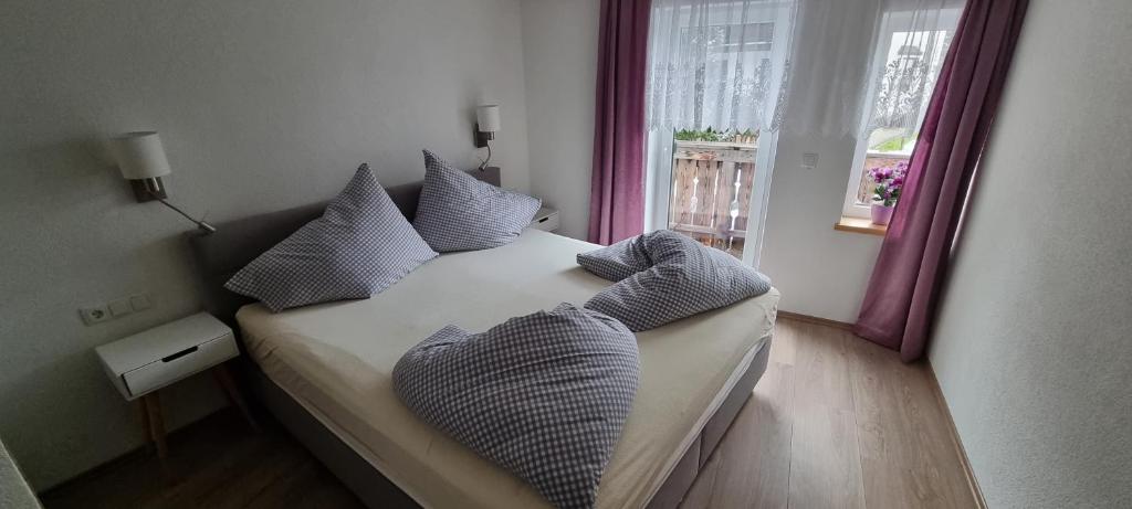 sypialnia z łóżkiem z poduszkami i oknem w obiekcie Schäfflers Ferienwohnungen w mieście Lermoos