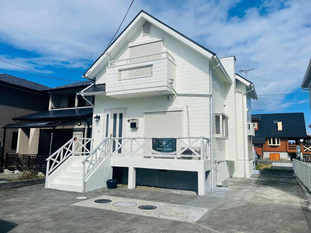 a white house with a staircase on the side of it at Shanshui House Shin asahi in Takashima