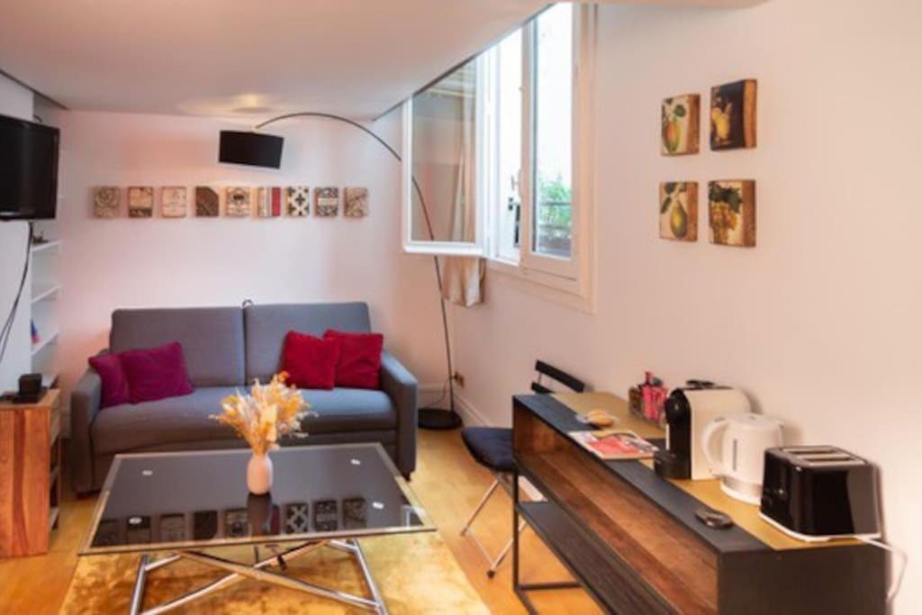 een woonkamer met een bank en een tafel bij Haut MaraisJolie duplex 33m2… in Parijs