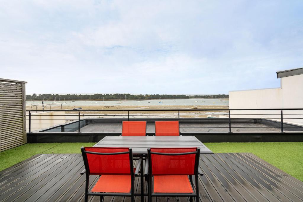 a table and chairs on a deck with a view of an airport at Appartement vue mer a lIle Tudy in Île-Tudy