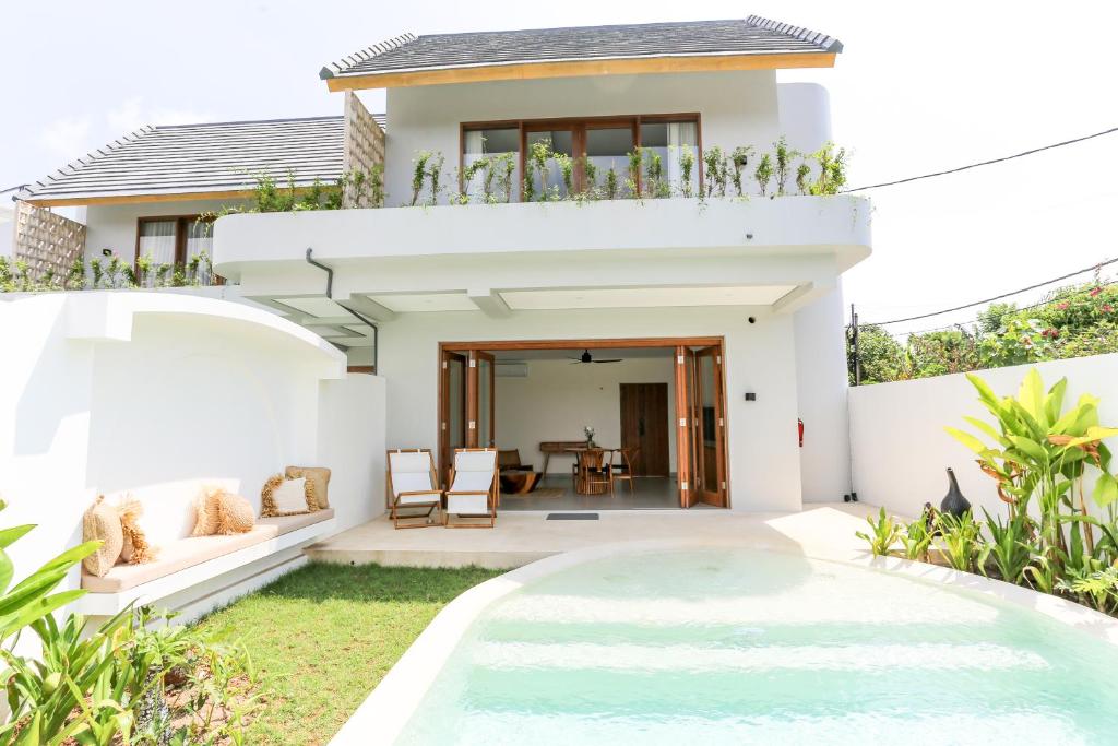 a villa with a swimming pool in front of a house at Shoreline Villas Bingin in Uluwatu