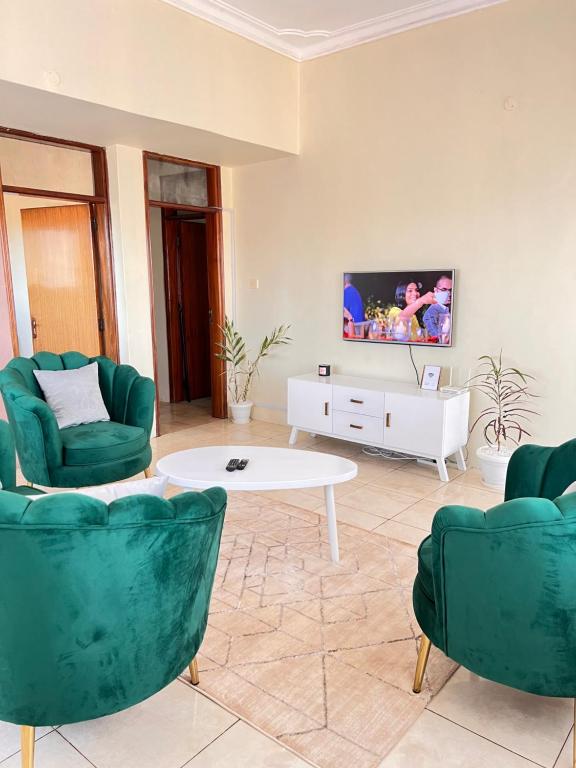 uma sala de estar com duas cadeiras verdes e uma mesa branca em Le Vert Homes em Kampala