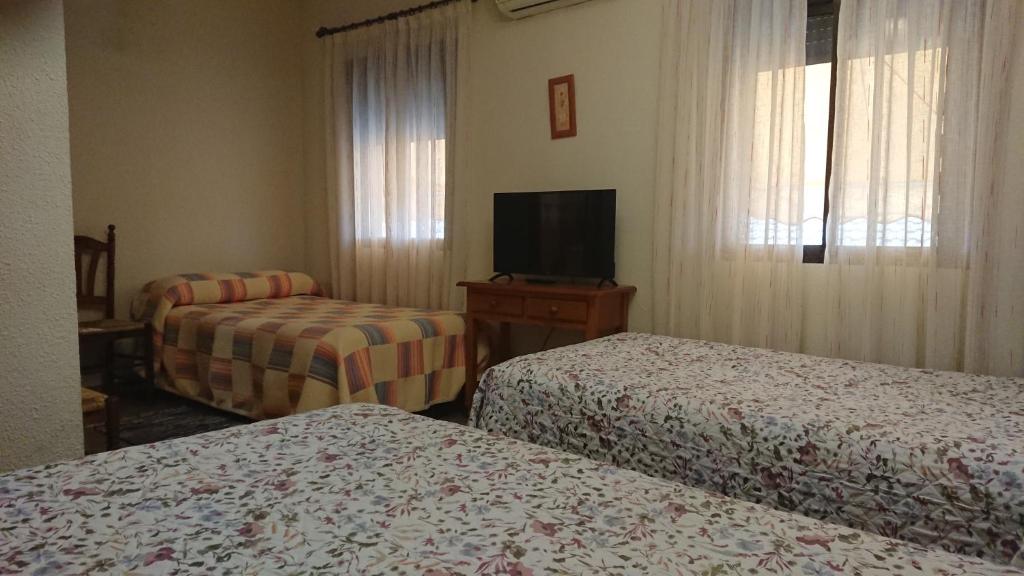 a hotel room with two beds and a flat screen tv at Posada La Reja in Malpica