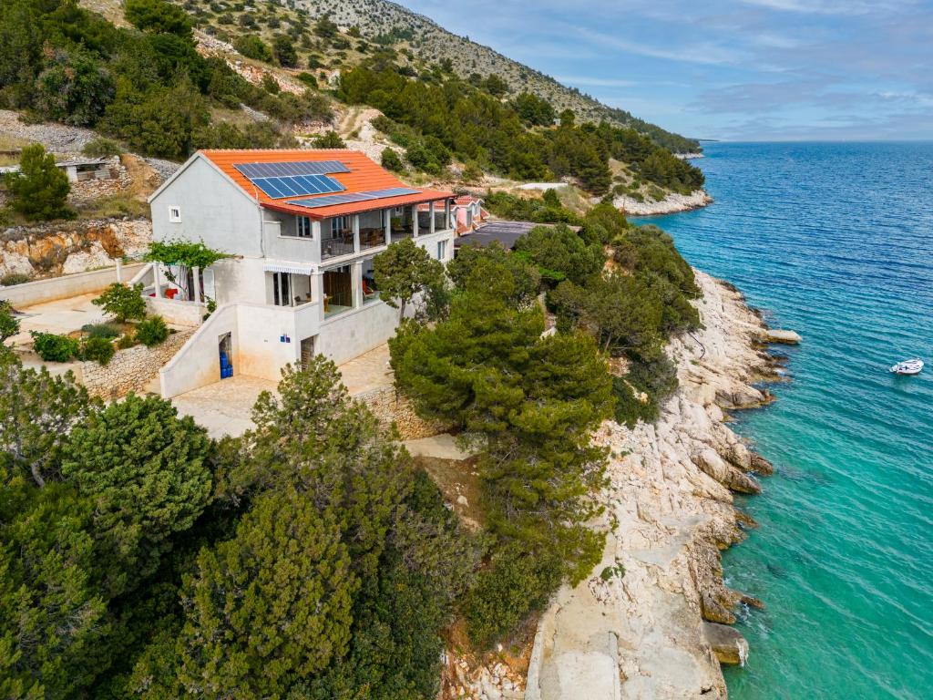 an aerial view of a house on a cliff next to the water at Rooms Plaža Divuje in Murvica