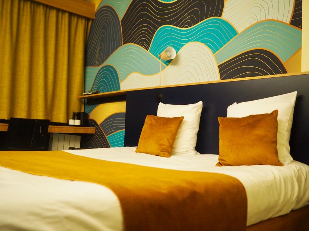 una camera d'albergo con un grande letto con cuscini arancioni di Hôtel Central Parc Oyonnax a Oyonnax