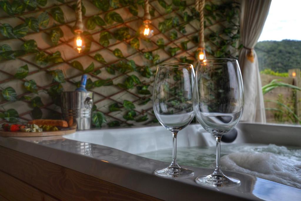 dos copas de vino sentadas en un mostrador junto a una bañera en Recanto Aloha Kaii, en Palhoça