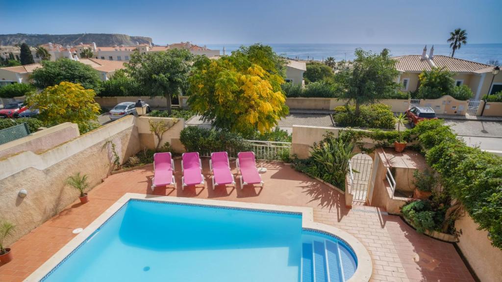 a swimming pool with two pink chairs next to a house at Vila Bela Nova Acácias 22 in Luz