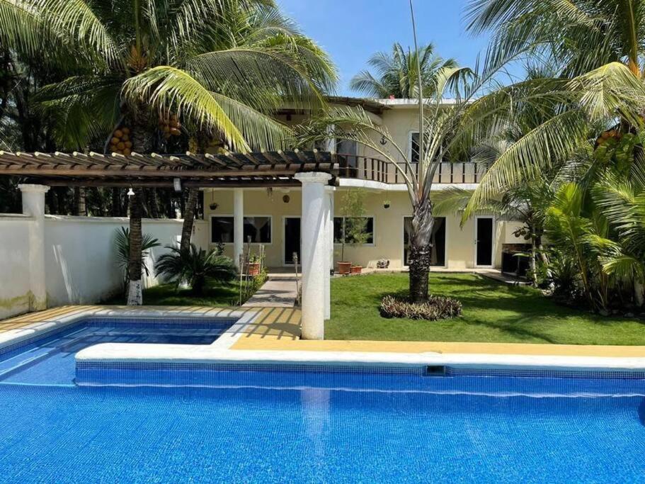 a villa with a swimming pool in front of a house at Casa Los Cocos Monterrico in Monterrico