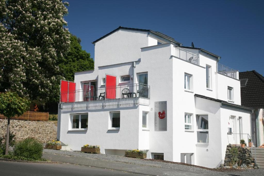 a white building with red doors and a balcony at Haus Hillebrand in Bad Honnef am Rhein