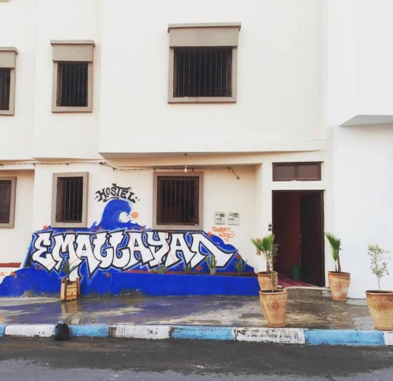 una pared cubierta de graffiti delante de un edificio en Emallayan Hostel, en Imsouane