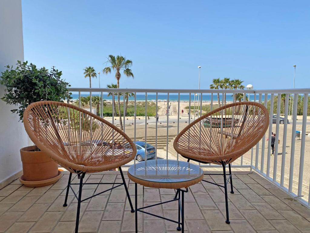 dwa krzesła i stół na balkonie z plażą w obiekcie Santa Barbara A Beach front apartment with sea view and garage in Conil w mieście Conil de la Frontera