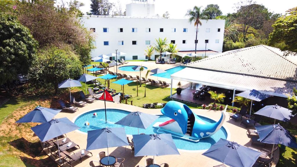 uma vista superior para uma piscina com guarda-sóis azuis e uma piscina em Valinhos Plaza Hotel em Valinhos