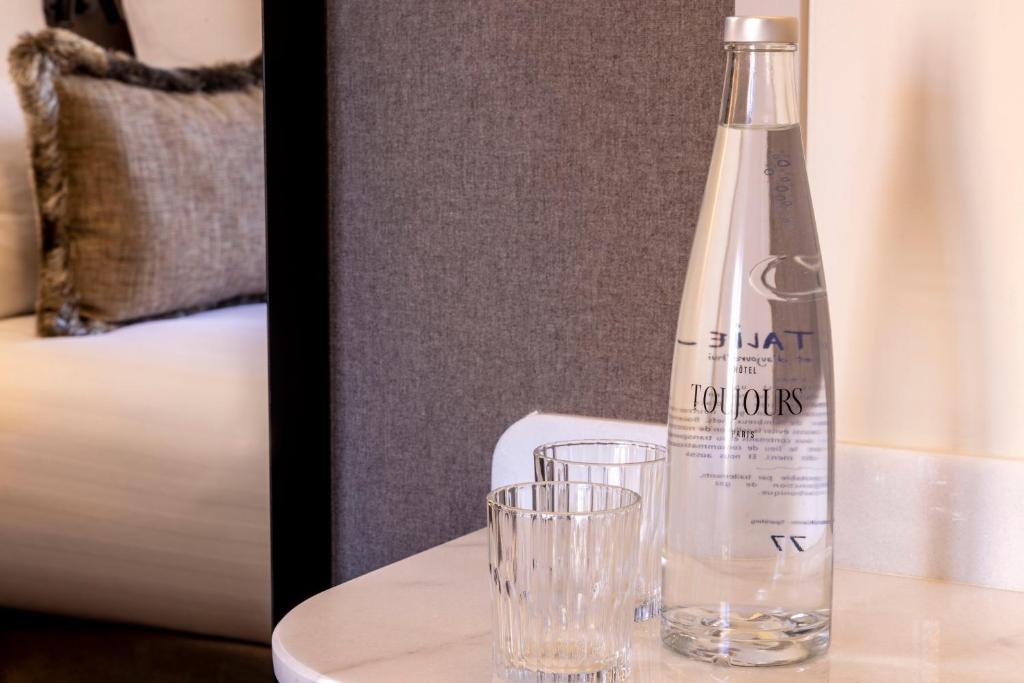 a bottle of water and glasses on a table at Hôtel Toujours &amp; Spa in Paris