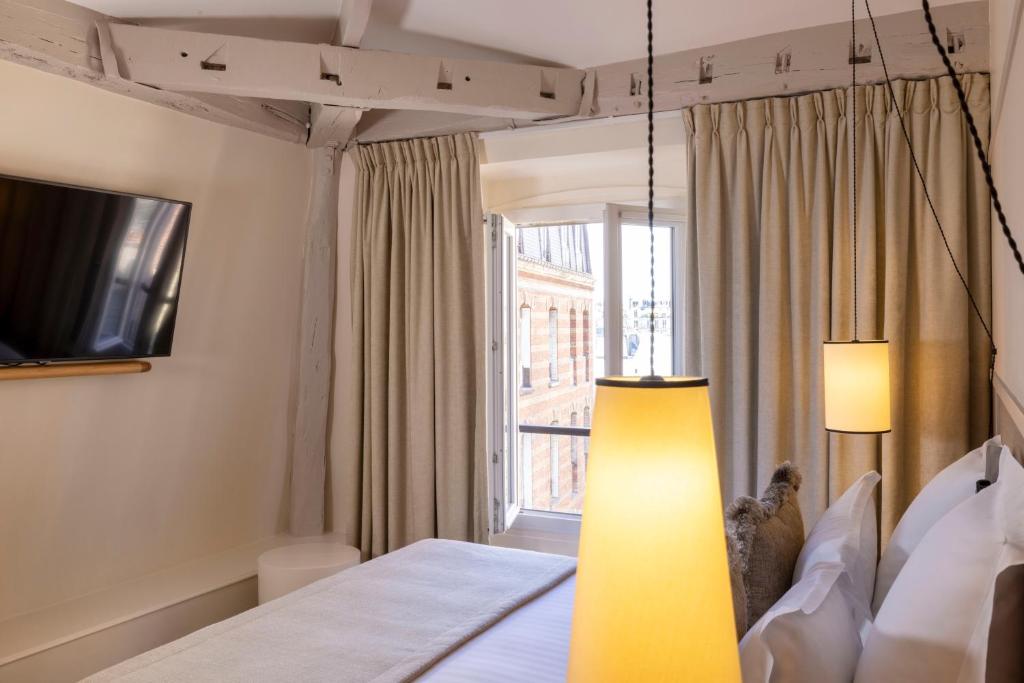 a bedroom with a bed and a large window at Hôtel Toujours &amp; Spa in Paris