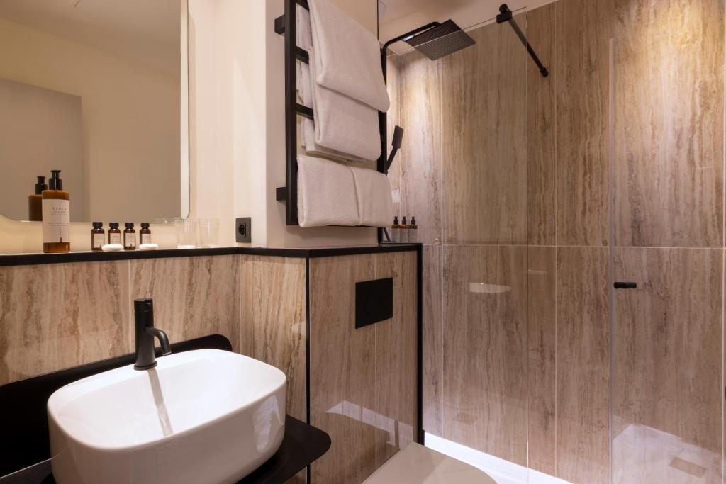 a bathroom with a white sink and a shower at Hôtel Toujours &amp; Spa in Paris