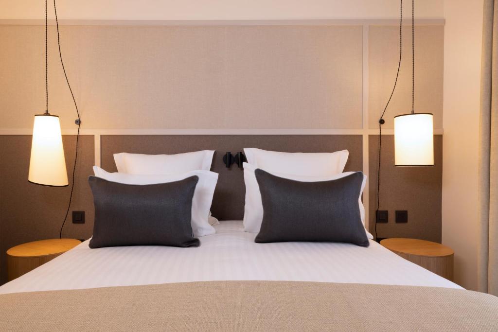 a bedroom with a bed with two pillows and two lights at Hôtel Toujours &amp; Spa in Paris