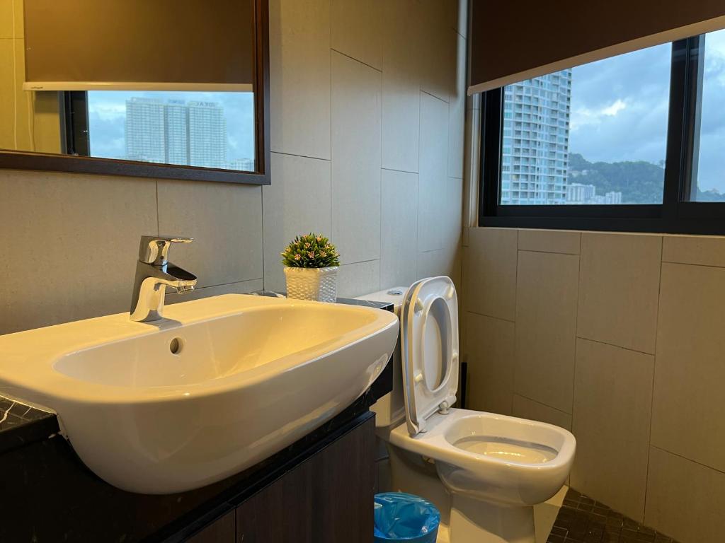 a bathroom with a sink and a toilet with a window at The Landmark Comfort Relax Spacious Sea View By IZ in Tanjong Tokong