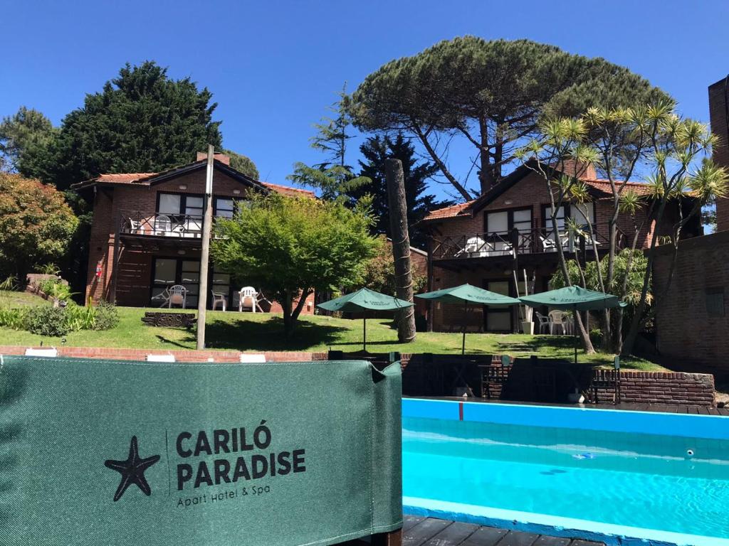 a house with a sign in front of a swimming pool at Cariló Paradise Apart Hotel & Spa in Carilo