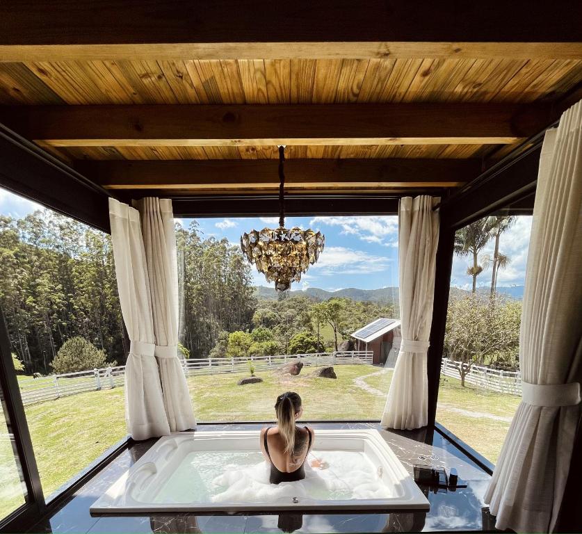 a woman in a bath tub in a room with a window at Alameda dos Ipês, casa completa, para toda família in Santo Amaro da Imperatriz