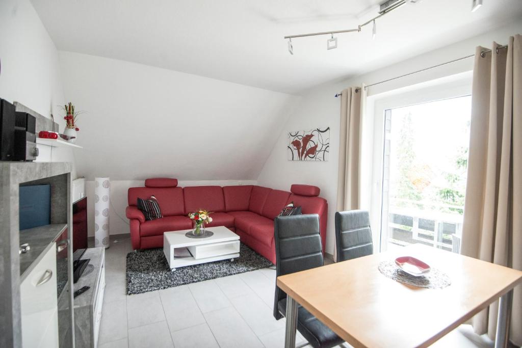 ein Wohnzimmer mit einem roten Sofa und einem Tisch in der Unterkunft Wietheger´s Gästehaus Centrum in Willingen