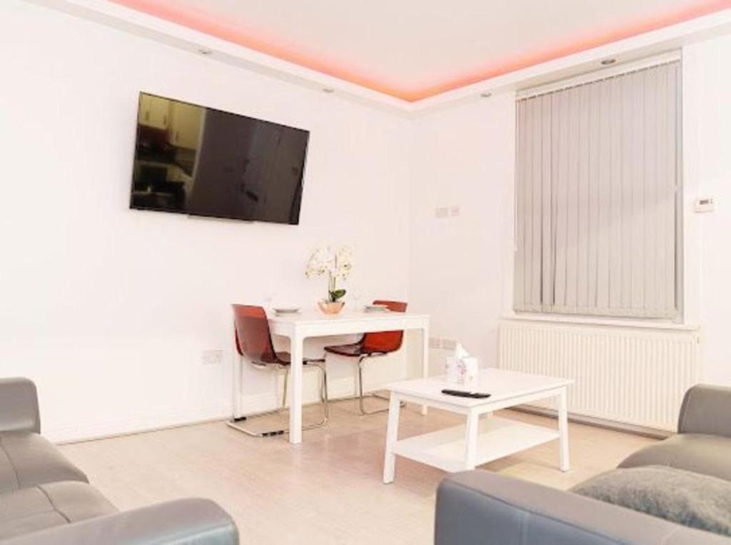 - un salon avec une table et une télévision murale dans l'établissement Excel House Serviced Apartments, à Leeds