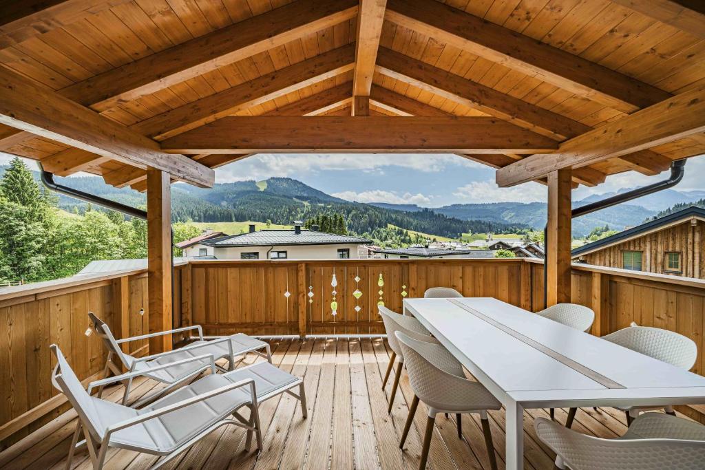 a wooden deck with a white table and chairs at Dachstein West Apartment T4 in Russbach am Pass Gschütt