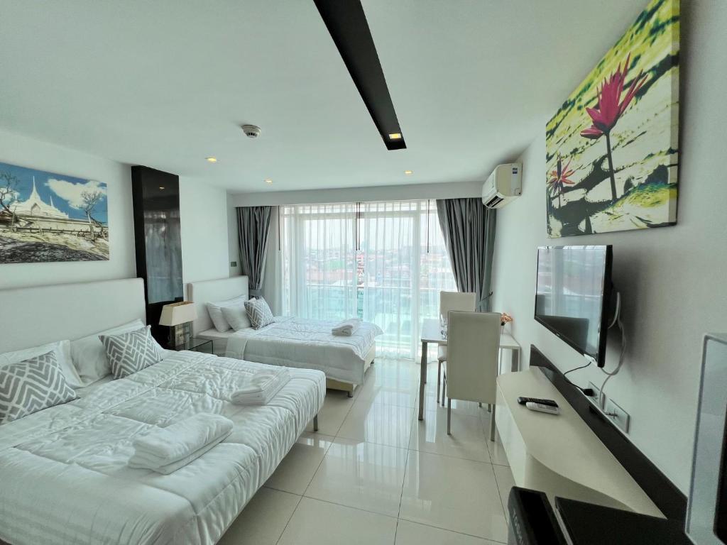 a hotel room with two beds and a television at TRENDY Studio in City Center Residence in Pattaya