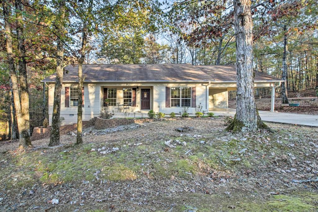 a small white house in the woods with a tree at Tranquil Family Retreat with Fire Pit and Grill! in Hot Springs Village