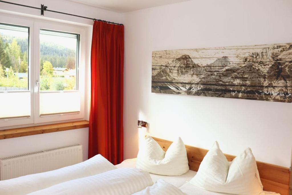 a bedroom with a white bed with a red curtain at Zottlhof- dein Urlaubszauber auf 1.200m in Leutasch
