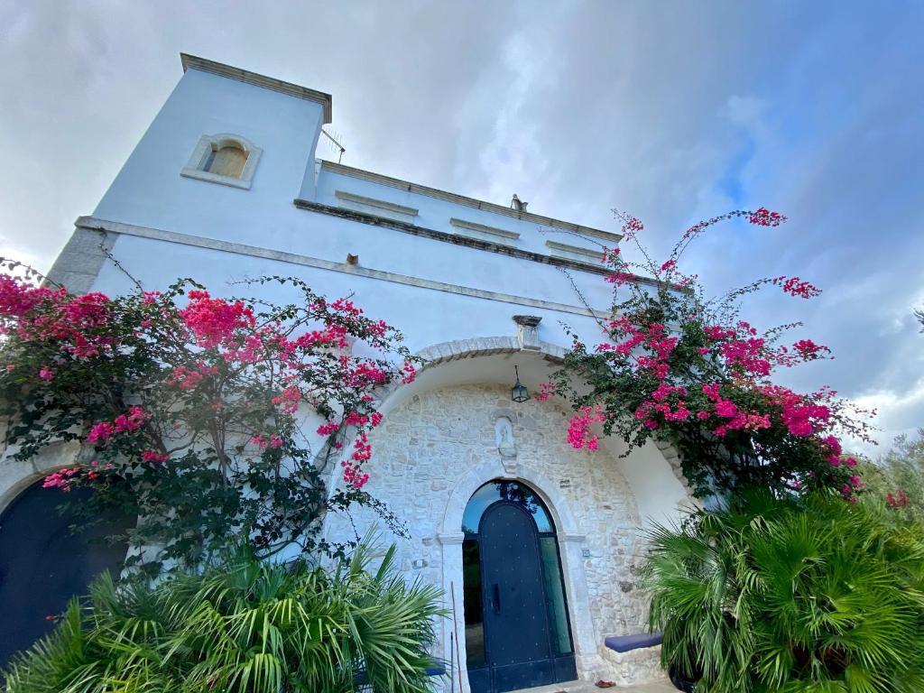 un bâtiment blanc avec des fleurs roses sur lui dans l'établissement Villa del 1700 immersa nel verde, Poggio al Sole Vieste, à Vieste
