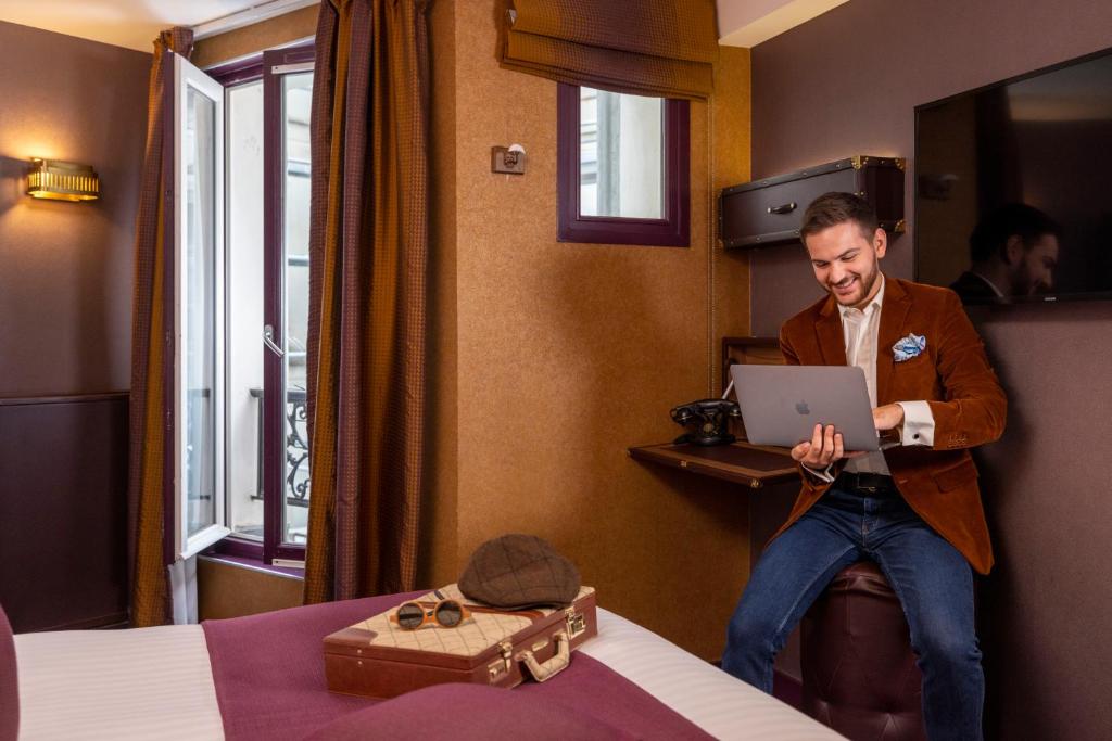 a man sitting in a hotel room with a laptop at Hotel Whistler - Gare du Nord in Paris