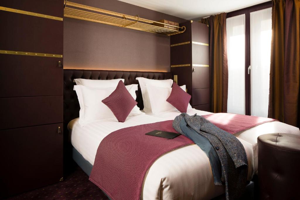 a bedroom with a large bed with pink and white pillows at Hotel Whistler - Gare du Nord in Paris