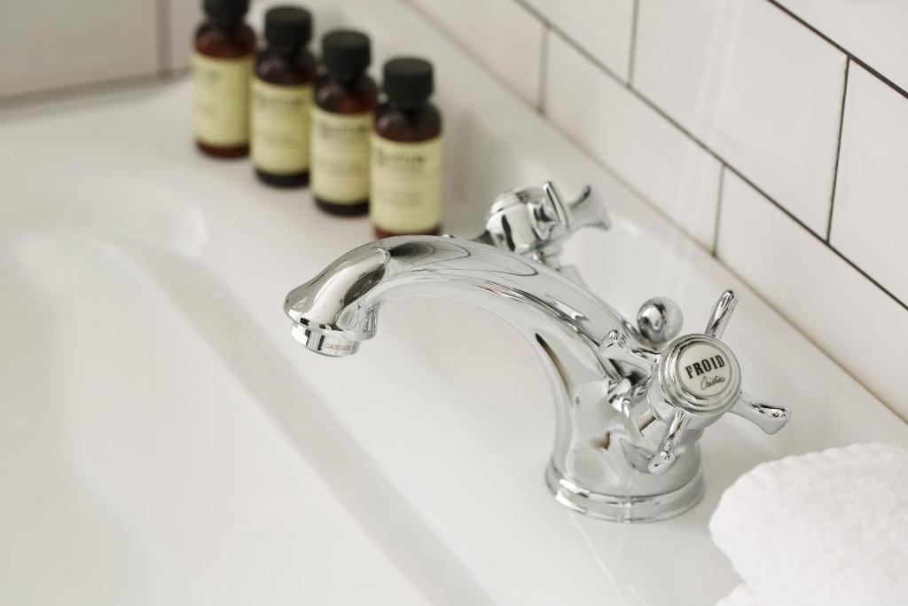 a bathroom sink with a silver faucet and three bottles at Hotel Whistler - Gare du Nord in Paris