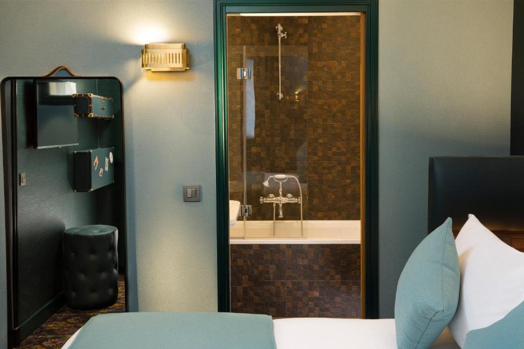 a bedroom with a bathroom with a shower and a bed at Hotel Whistler - Gare du Nord in Paris