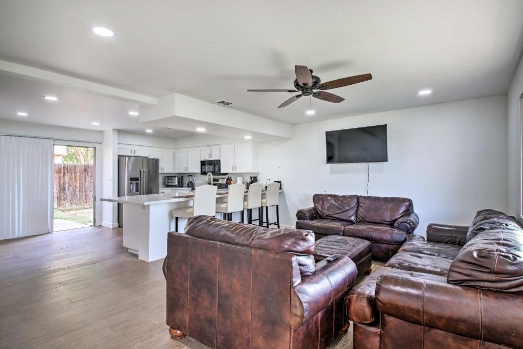 a living room with leather furniture and a ceiling fan at Central Bakersfield Townhome with Private Patio in Bakersfield