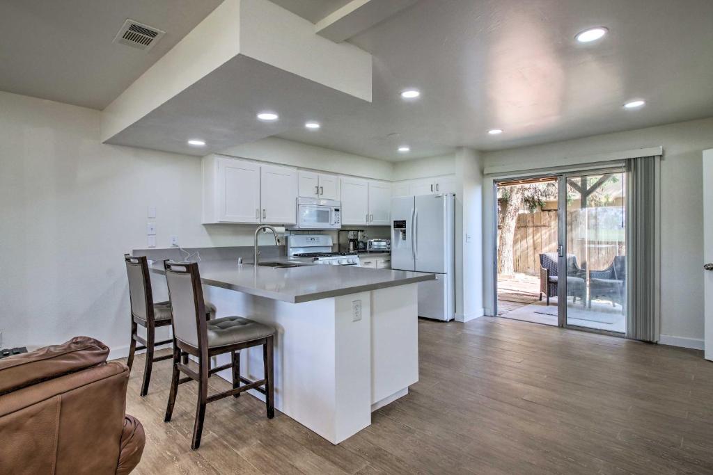 Una cocina con gabinetes blancos y un mostrador con sillas. en Comfy Bakersfield Townhome - Fire Pit and Patio, en Bakersfield
