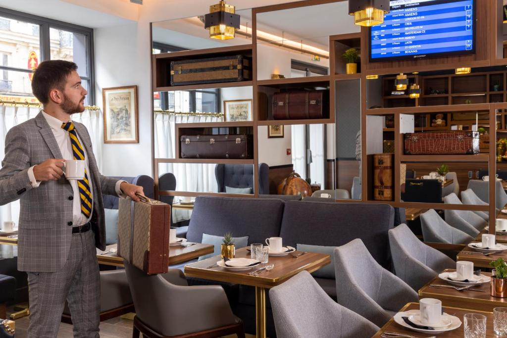 a man drinking a cup of coffee in a restaurant at Hotel Whistler - Gare du Nord in Paris