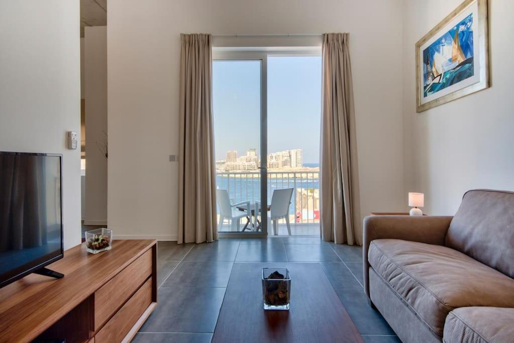 uma sala de estar com um sofá e uma televisão de ecrã plano em VALLETTASTAY - HARBOR VIEW GEM -SEA VIEW 2 BED APT em Valletta