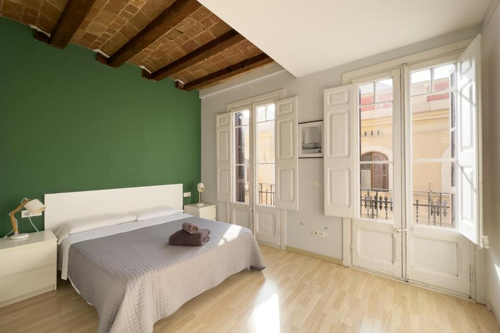 1 dormitorio con cama blanca y paredes verdes en ApartEasy - Gracia Apartments, en Barcelona