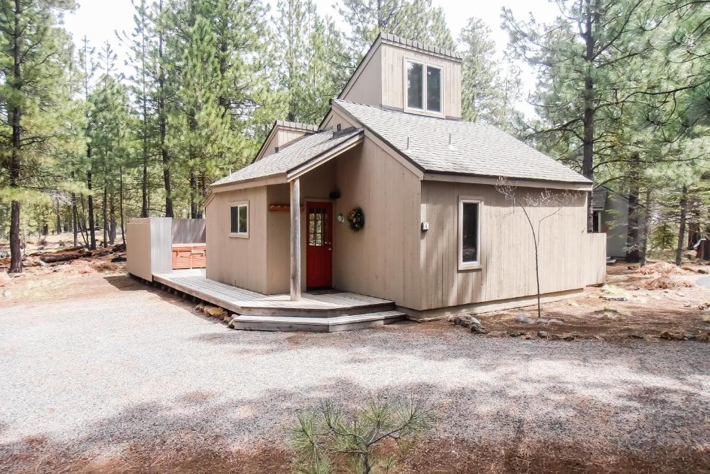 une petite maison avec une porte rouge dans les bois dans l'établissement Mules Ear Trail Cabin 8, à Black Butte Ranch