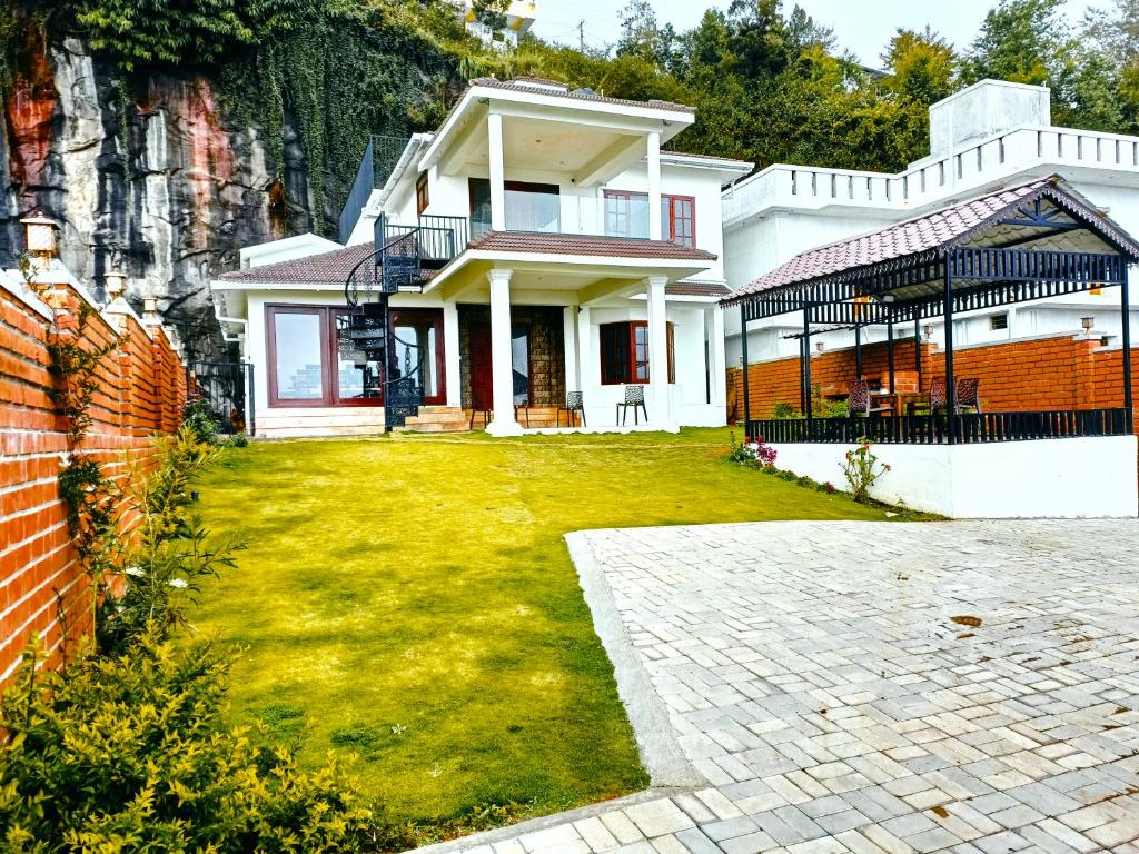 een groot wit huis met een grasveld bij Villa de Montana in Kodaikānāl