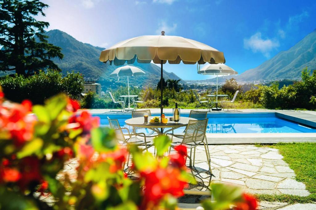 einen Tisch mit einem Sonnenschirm neben einem Pool in der Unterkunft Montebello in Lecco