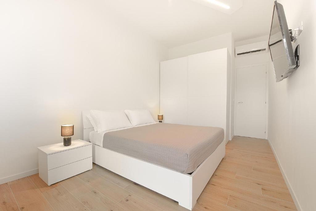 a white bedroom with a white bed and a tv at Milleventi Apartments in Bologna