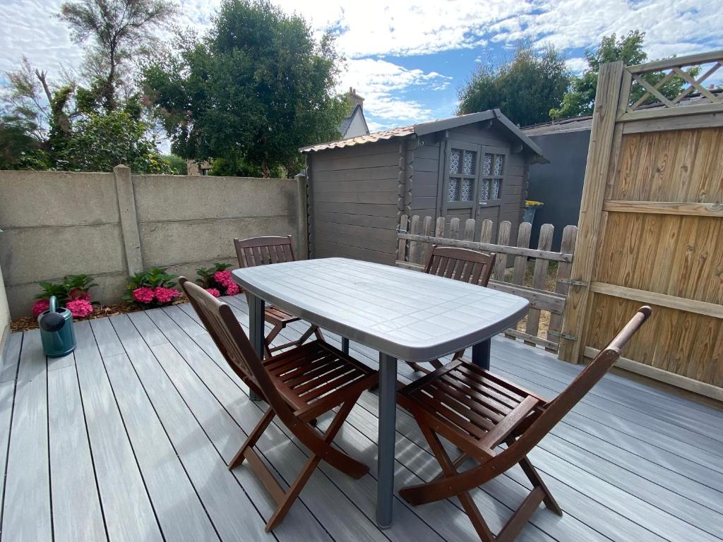 une table et deux chaises sur une terrasse en bois dans l'établissement Maison de pêcheur avec terrasse à 450m de la plage à TREGASTEL - Réf 184, à Trégastel