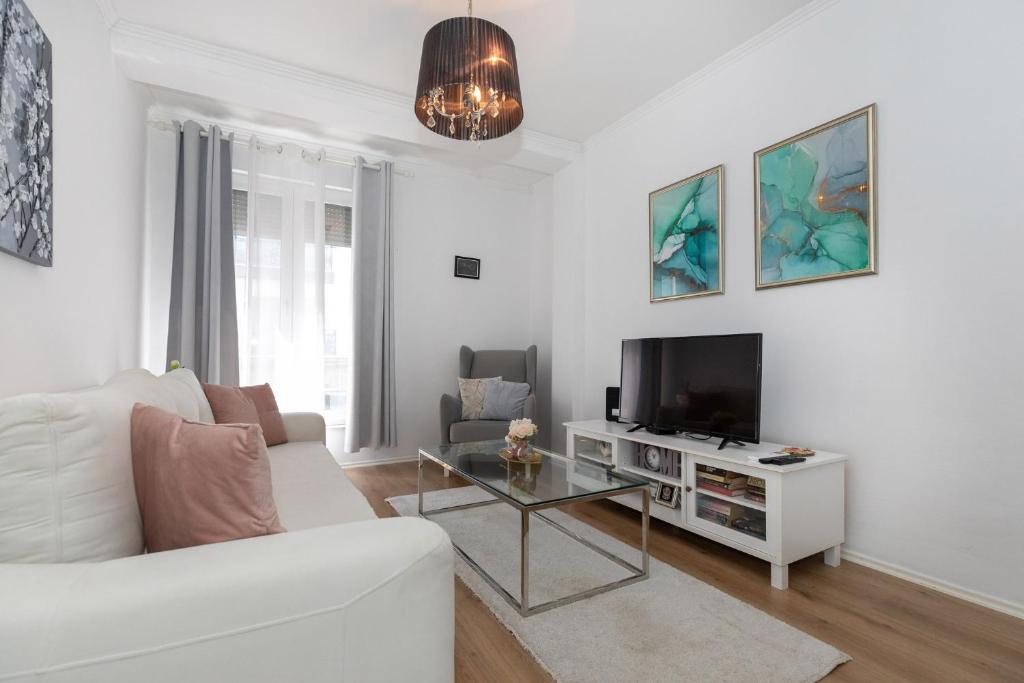 ein Wohnzimmer mit einem weißen Sofa und einem TV in der Unterkunft Happy Apartment II in Mostar