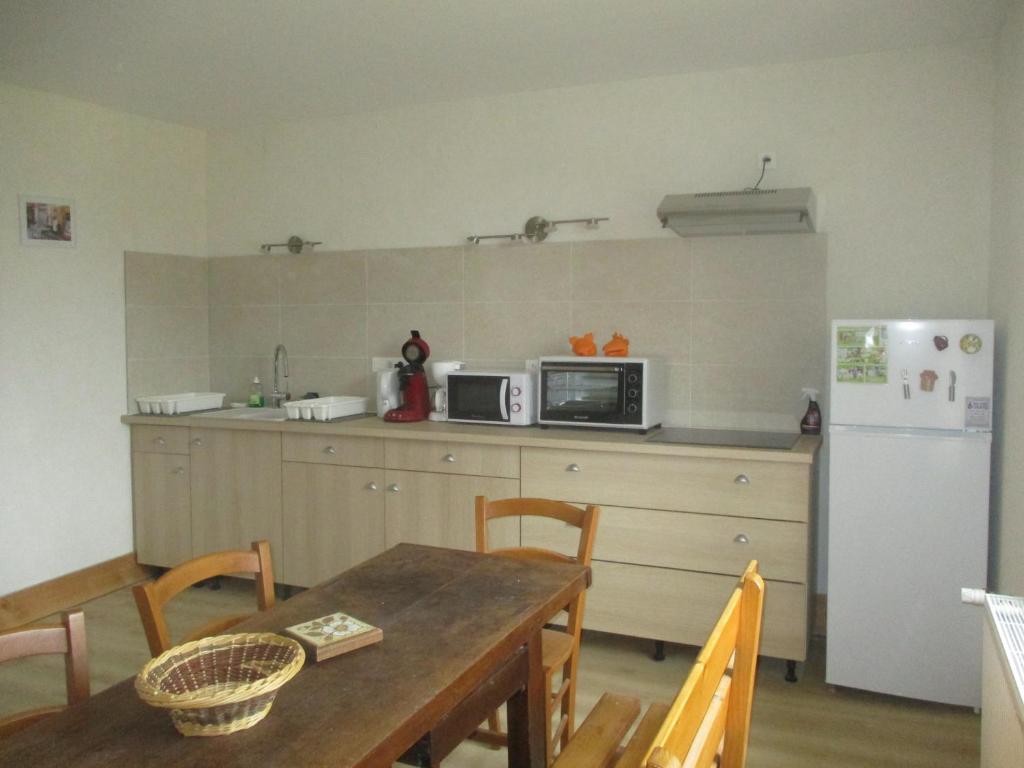 a kitchen with a table and a microwave and a refrigerator at Appartement La petite Résie in La Résie-Saint-Martin