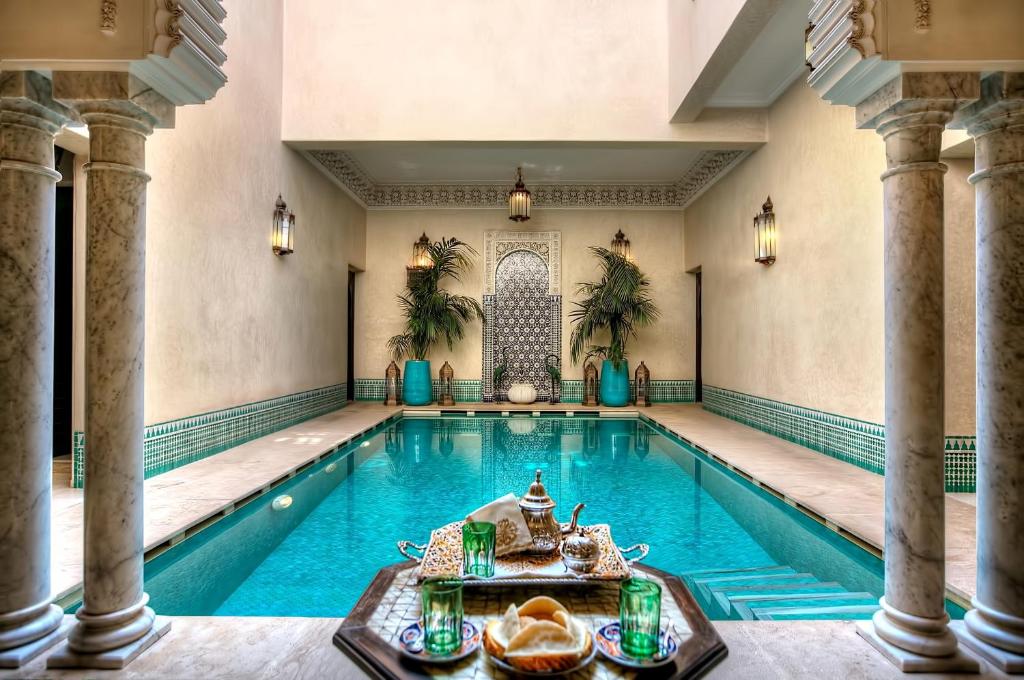 una piscina cubierta con columnas y una piscina de hidromasaje en Riad Kniza en Marrakech