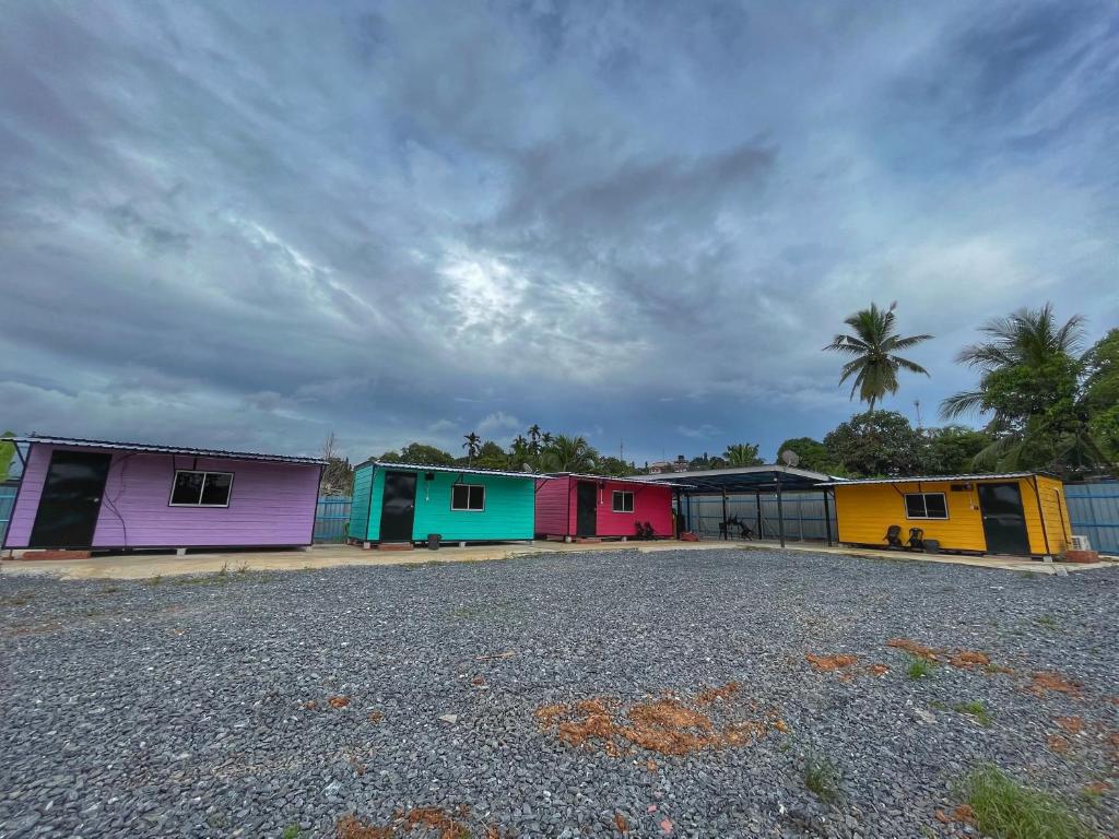 a row of colorful buildings with a palm tree in the background at Padang Besar Rainbow Cabin Homestay in Padang Besar