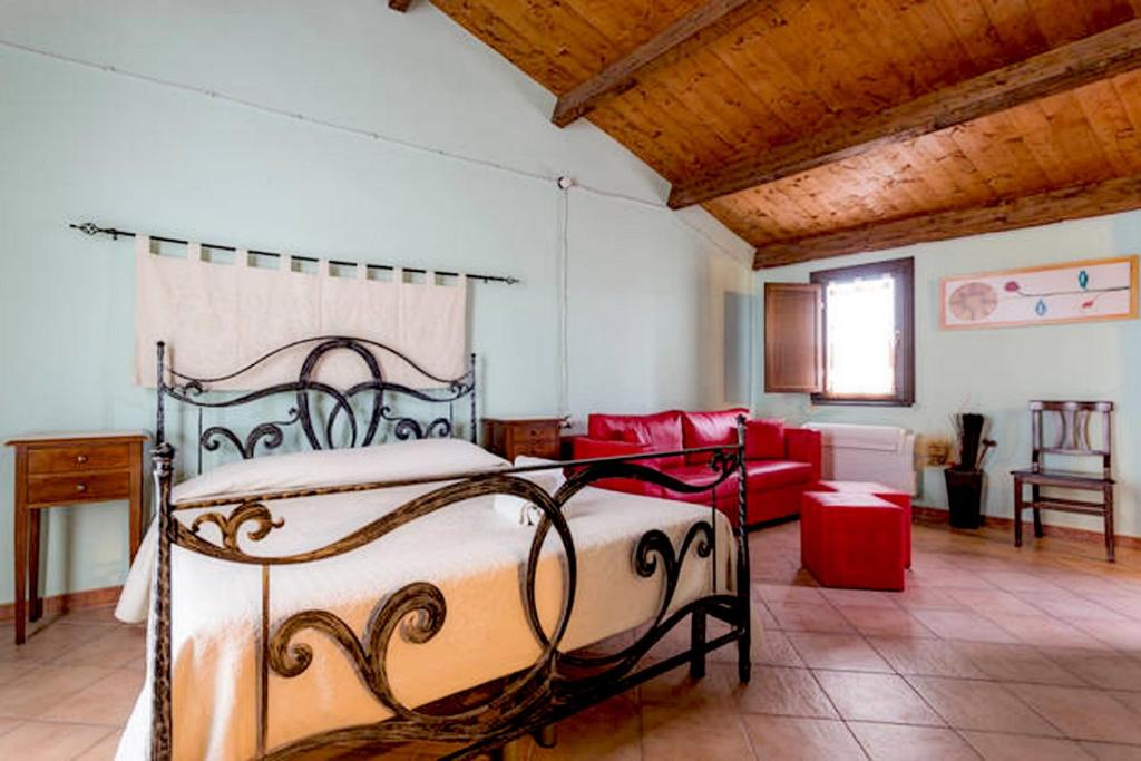a bedroom with a bed and a red couch at Sa Domo De Alene in Bosa
